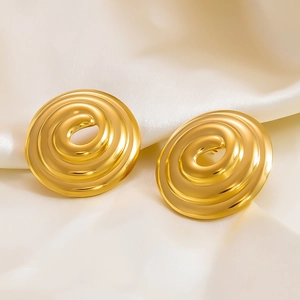 Macro shot of gold spiral textured earrings on elegant white silk background