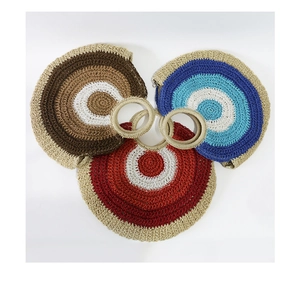 Three circular straw bags in brown, blue, and red with radial woven patterns