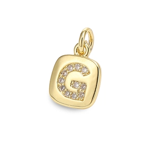 Macro detail of gold square pendant with letter G design and cubic zirconia inlay