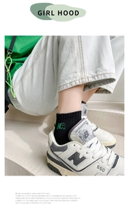 Detailed view of black combed cotton sock with green NA letter embroidery on ankle
