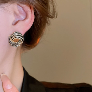Macro view of vintage gold swirl earrings with black enamel and sparkling crystals