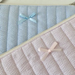 Close-up of quilted stripe laptop and tablet sleeves with satin bow detail and zippers