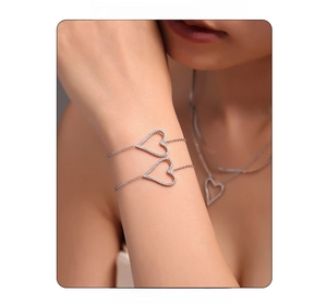 Detailed view of silver heart jewelry set with micro-pave crystals on a model