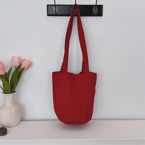 Detalle del bolso de hombro rojo acolchado con costuras verticales y diseño minimalista