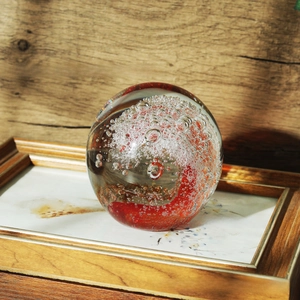 Macro shot of glass crystal ball featuring a red swirl vortex with artistic fine bubbles