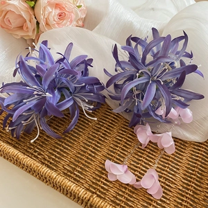 Vue détaillée de pinces à cheveux fleurs en tissu violet avec pompons sur plateau tressé