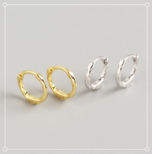 Macro shot of twisted silver and gold hoop earrings with textured metallic finish