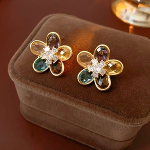 Macro view of flower stud earrings featuring colorful faceted stones in golden setting