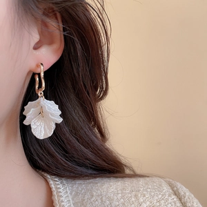 Elegant floral pearl earring featuring layered white petals and a golden hook on model