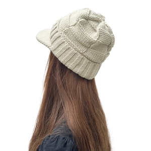 Détail du bonnet en maille beige avec visière montrant la texture chaude pour l'hiver