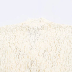 Detailed close-up of cream-colored lace fabric with intricate hollow-out embroidery pattern