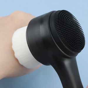 Detailed close-up of the dual-sided facial brush with soft white bristles and black silicone