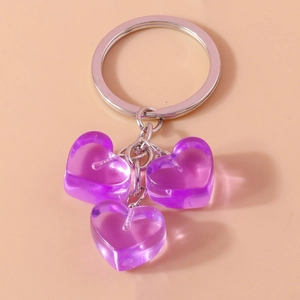 Close-up of three purple translucent heart pendants on a silver metal keychain ring
