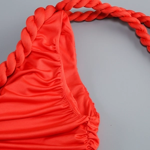 Detailed view of red dress featuring pleated fabric and braided shoulder strap design