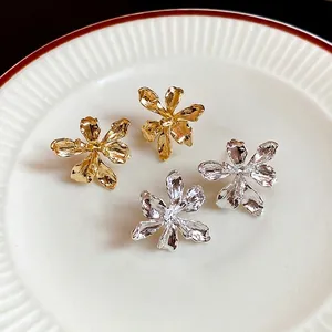 Minimalist 3D metal flower stud earrings in gold and silver finish with textured petals