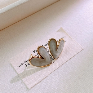 Macro shot of heart-shaped gold-rimmed earrings with white marble texture on fabric