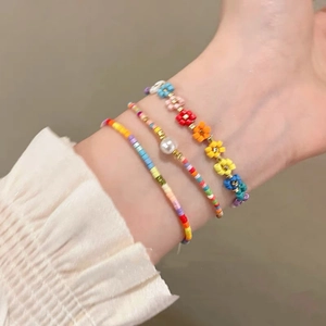 Rainbow beaded bracelet set with colorful flower charms and pearls on model wrist