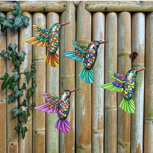 Set of four colorful metal hummingbird wall decors with mosaic patterns on a bamboo fence