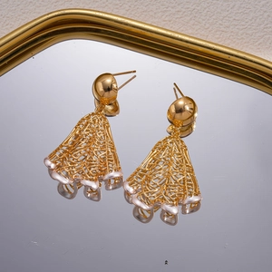 Detail view of 18K gold plated mesh earrings on a mirror tray with golden reflections