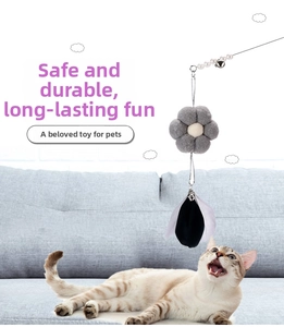 Macro detail of cat wand featuring felt flower, bell, and feathers for interactive play