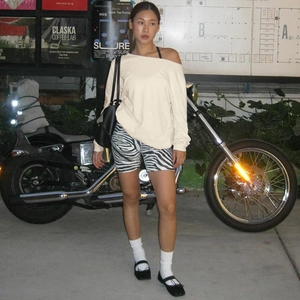 Urban street style look featuring a beige off-shoulder long sleeve top and zebra print shorts