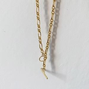 Detail of gold chain necklace with industrial link design and classic T-bar toggle closure