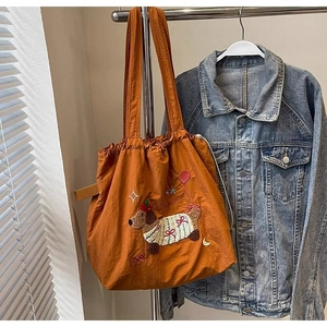 Detail of orange canvas tote bag with puppy embroidery and drawstring closure