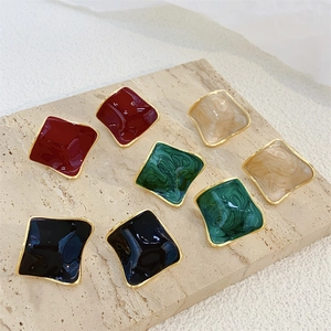 Flat lay of square enamel stud earrings in burgundy, dark green, black and marble beige