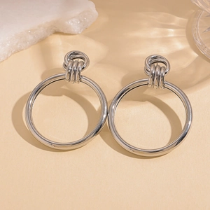 Macro view of silver knot hoop earrings with metallic finish on textured background