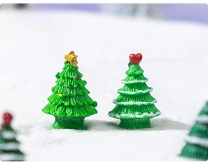 Close-up of miniature resin Christmas trees with colorful ornaments and snow finish