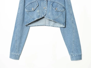 Detalle de chaqueta vaquera corta azul claro con botones plateados y bolsillos