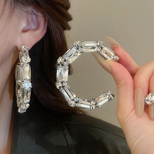 Détail macro de boucles d'oreilles C argentées avec cristaux carrés et ronds brillants