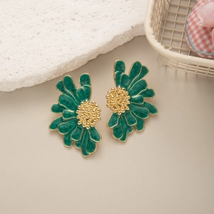 Close-up of green enamel daisy floral earrings with golden textured center and edges