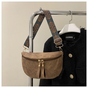 Détail d'un sac bandoulière rétro marron avec une large sangle brodée ethnique