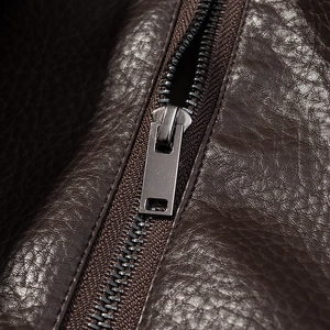 Détail macro de la texture du similicuir marron et du zip métallique sur la veste de moto