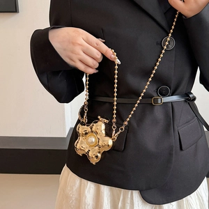 Mini sac chaîne fleur dorée avec une grande perle blanche sur un blazer noir