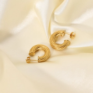 18K gold-plated stainless steel twisted hoop earrings on beige satin fabric backdrop