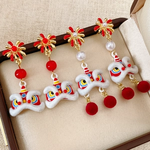 Detail of lion dance earrings with red pompom, enamel patterns and pearls in a gift box