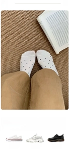 Detail of white cotton no-show socks with black polka dots worn with casual khaki pants