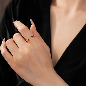 Gros plan d'une élégante bague ouverte en forme de cœur or rose portée au doigt