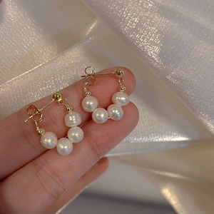 Elegantes pendientes de perlas con baño de oro sobre una tela de seda brillante