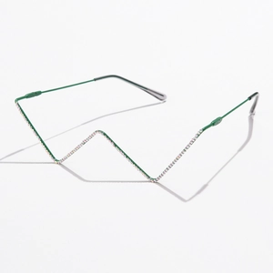 Detail of green metal W-shaped eyeglass frame with sparkling colored rhinestones