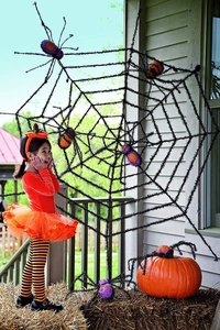 Giant black fuzzy spider web with colorful plush spiders for Halloween porch decoration