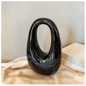 Modern black ceramic oval vase with hollow design and smooth glossy finish for home decor