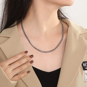 Silver stainless steel Cuban chain necklace with OT clasp on model wearing beige blazer