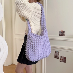 Detailed view of purple popcorn bubble fabric texture on a large capacity crossbody bag