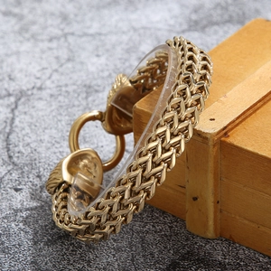 Close-up of golden punk lion head bracelet with intricate woven metal chain and round clasp