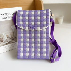 Detail of purple checkered knit crossbody bag with adjustable strap on a wooden shelf