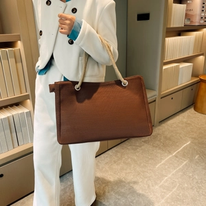 Detailed shot of large brown fabric tote bag featuring thick rope handles and spacious interior