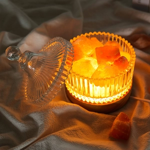 Crystal salt lamp with warm orange stones in a glass jar on a steady wooden base